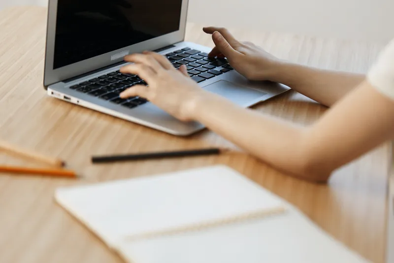 Focused businesswoman typing on a laptop at a wooden desk, showcasing productivity and a modern workspace environment ideal for remote work or freelancing