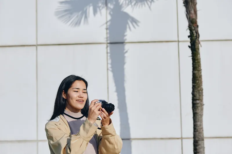 Photography, camera, woman, outdoor, candid, palm, wall, daylight, focus, creative, shot, casual, attire, urban, setting, serene, mood, natural, light, textures, expression, moment, exploration,