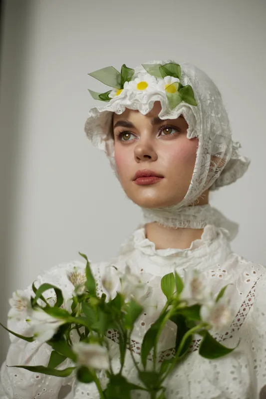 Young woman in vintage white dress with floral accents, holding a bouquet of white flowers, exuding a serene and nostalgic expression, perfect for spring or summer themes