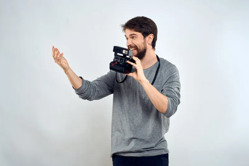 Фотограф-мужчина с профессиональной камерой, работа, студия, технологии, современное искусство, светлый фон