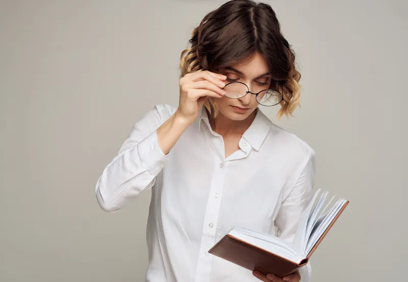 Деловая женщина в белой рубашке с книгой в руках, профессиональный вид