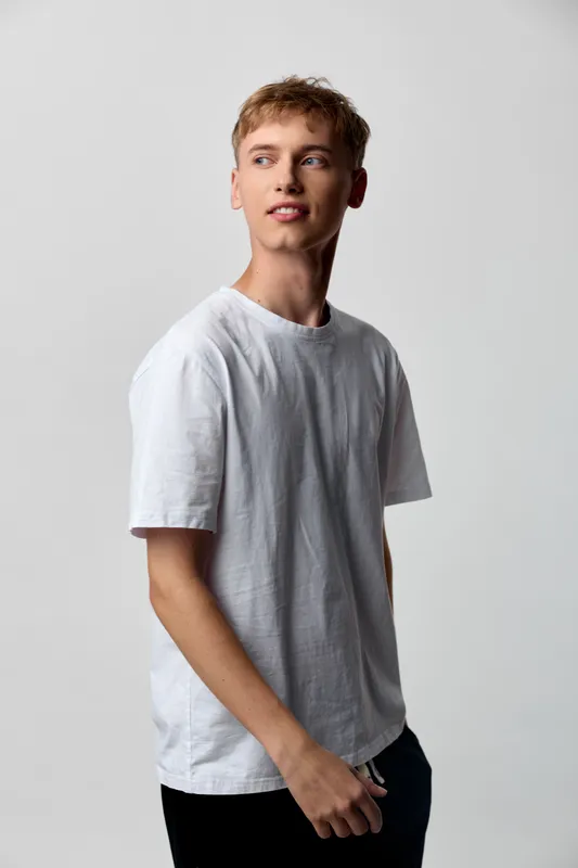 Man wearing a white t shirt in a clean studio setting, relaxed pose with soft lighting and a minimal background, showcasing casual fashion and lifestyle appeal for stock photography