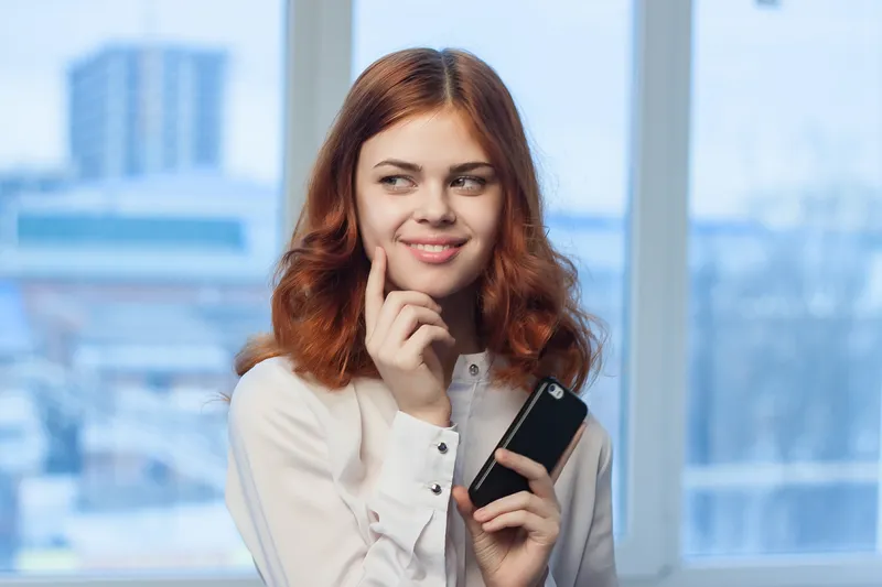 Деловая женщина в белой рубашке с телефоном в руках