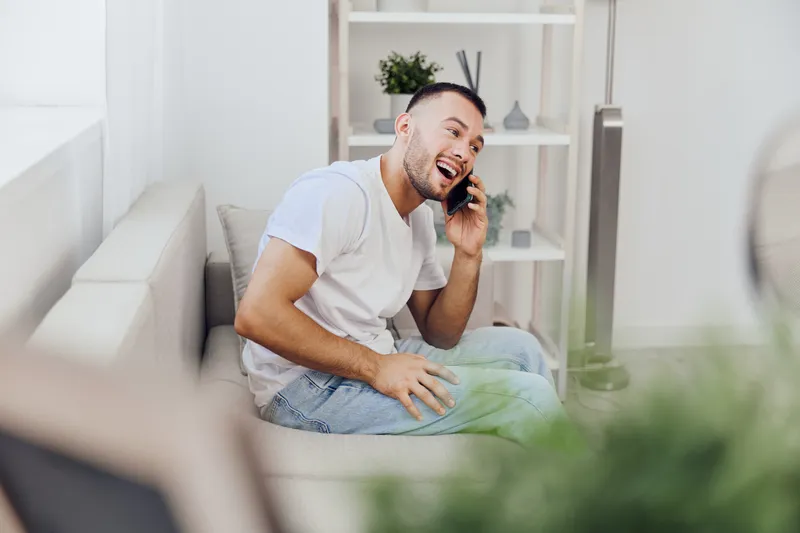 A cheerful man engaging in an emotional phone call, reflecting on mental health and modern communication challenges, capturing relatable moments of vulnerability.