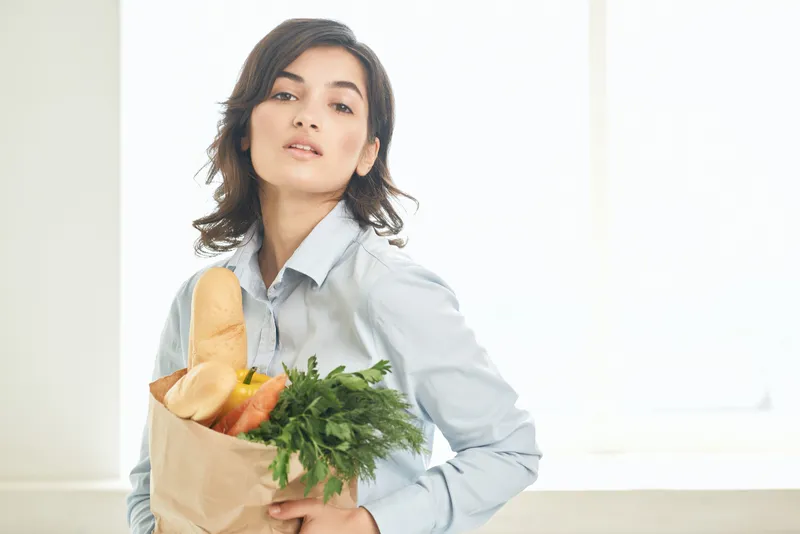 Женщина с пакетом продуктов на кухне
