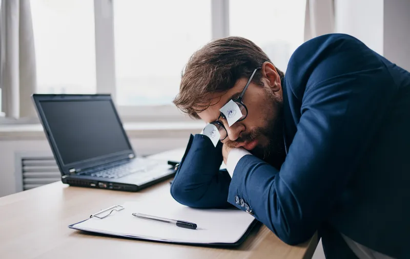 Мужчина в офисе сидит перед ноутбуком и работает