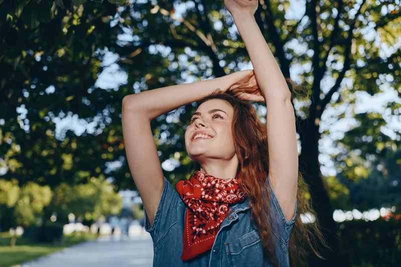 lifestyle woman in modern boho-western denim street style smiling outdoors with bright sunlight and film color effects, enjoying nature and freedom