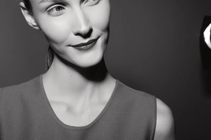 Close-up of a fair skinned Caucasian woman with subtle smile looking away. Black and white portrait with soft lighting creating a calm and elegant mood.