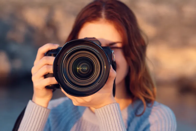 Женщина с профессиональным фотоаппаратом на открытом воздухе в горах, вид спереди