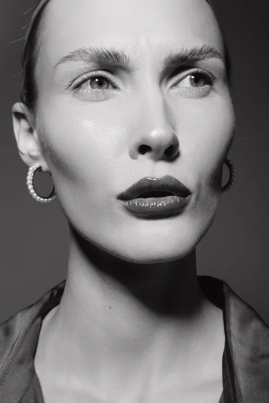White woman with pale skin and short hair looks serious in black and white close-up portrait fashion concept.