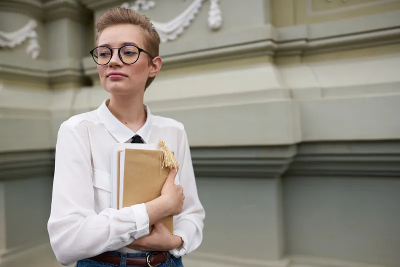 Женщина с короткой стрижкой на улице возле здания отдыхает и учится