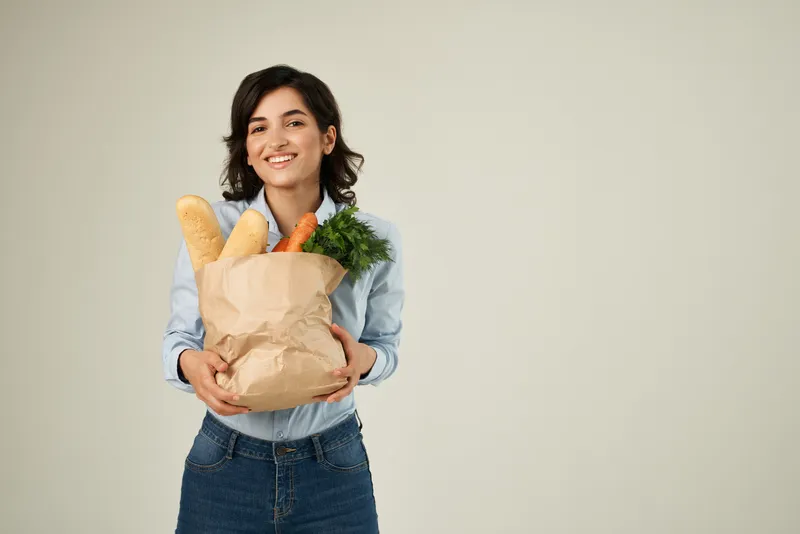 Улыбающаяся женщина с пакетом продуктов в супермаркете