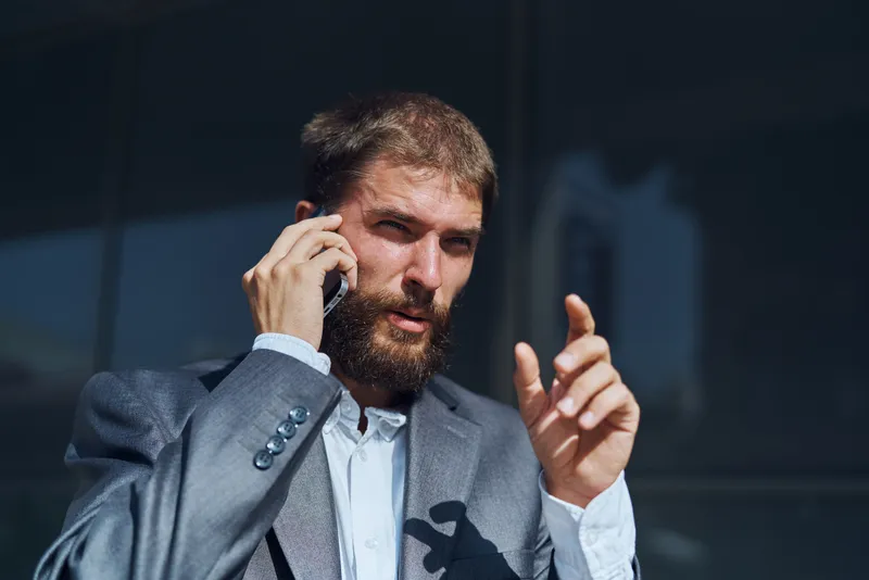Деловой мужчина в костюме разговаривает по телефону на улице, бизнесмен, руководитель, исполнительный директор