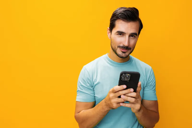 Счастливый мужчина улыбается, показывая зубы, и держит смартфон