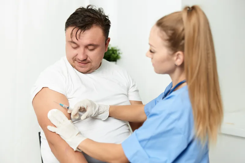 Женщина-врач делает прививку вакцины в руку пациента-мужчины