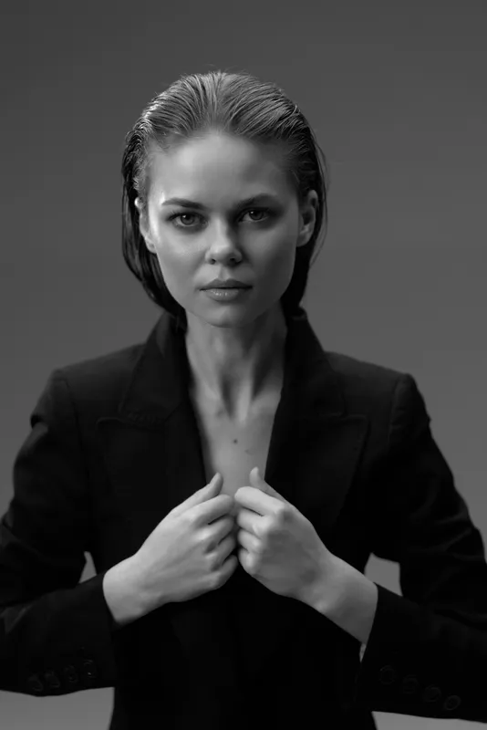 Black and white portrait of a serious woman in a blazer with slicked-back hair and confident expression