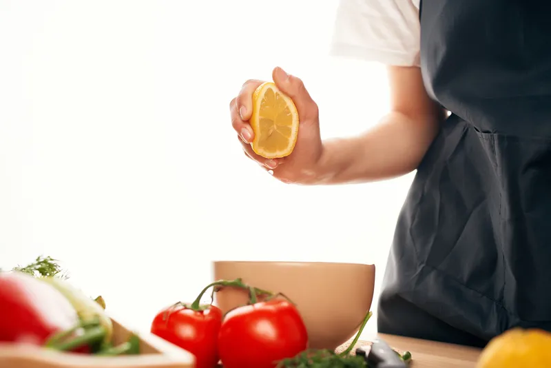 Лимон в руке на кухне, нарезка овощей для салата, приготовление еды
