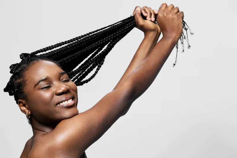 Joyful woman smiling with braided hair, showcasing her hair care routine against a clean white background Celebrating natural beauty and self expression through hair