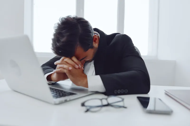 Мужчина на работе испытывает стресс, сидя в помещении