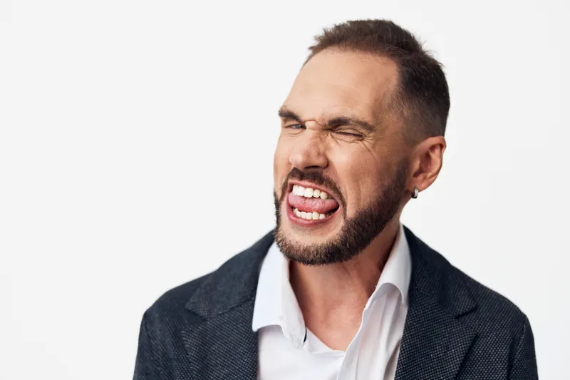 Business professional man on isolated colorful background expresses bold emotion with intense smile and confident stance, delivering energetic, expressive mood in a modern portrait.