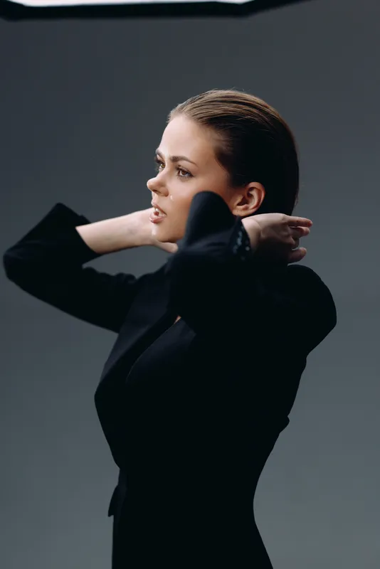 Profile of a thoughtful woman in a black outfit against a dark background, showcasing elegance and contemplative expression.