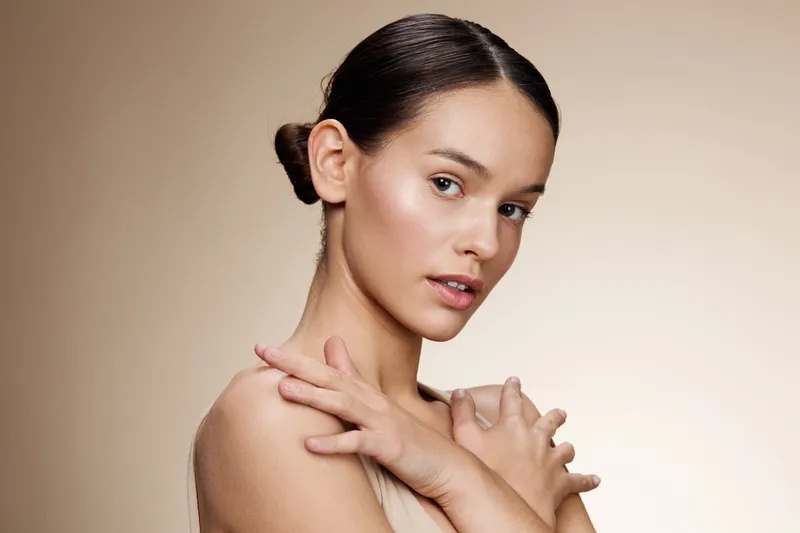 Elegant portrait of a young woman showcasing natural beauty with soft lighting and neutral tones, emphasizing skin texture and gentle expression