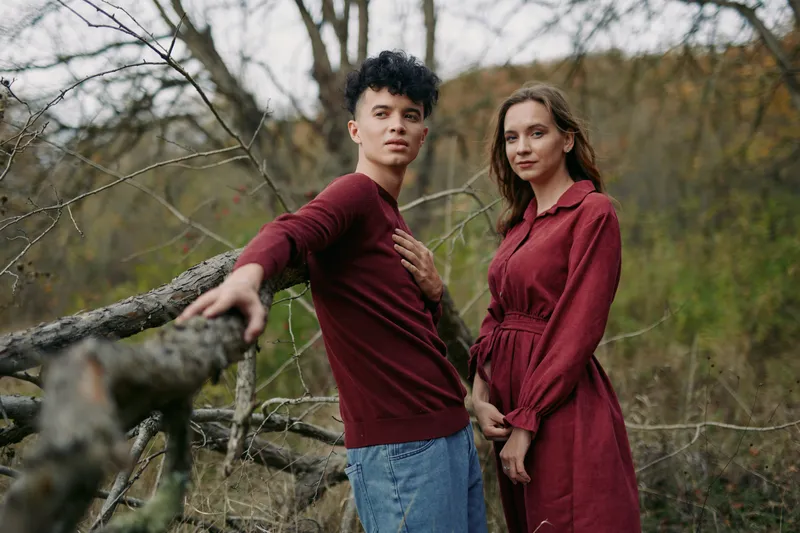Two individuals stand by a weathered wooden fence, sharing a candid moment that conveys tenderness, authenticity, and credibility in warm, natural light and sincere connection.