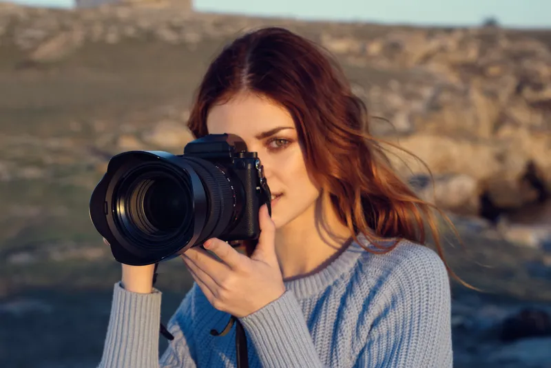 Веселая женщина-фотограф на фоне скалистых гор, пейзаж, отдых на природе