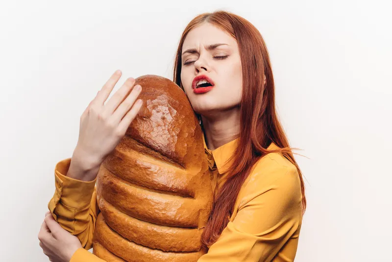 Весёлая женщина с ярким макияжем обнимает каравай руками