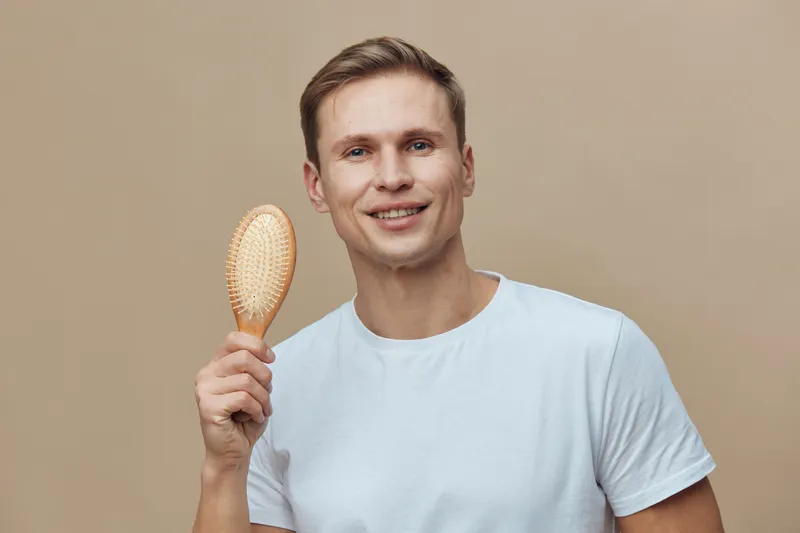Smiling young caucasian man hold hairbrush white t-shirt user digital detox concept isolated neutral background