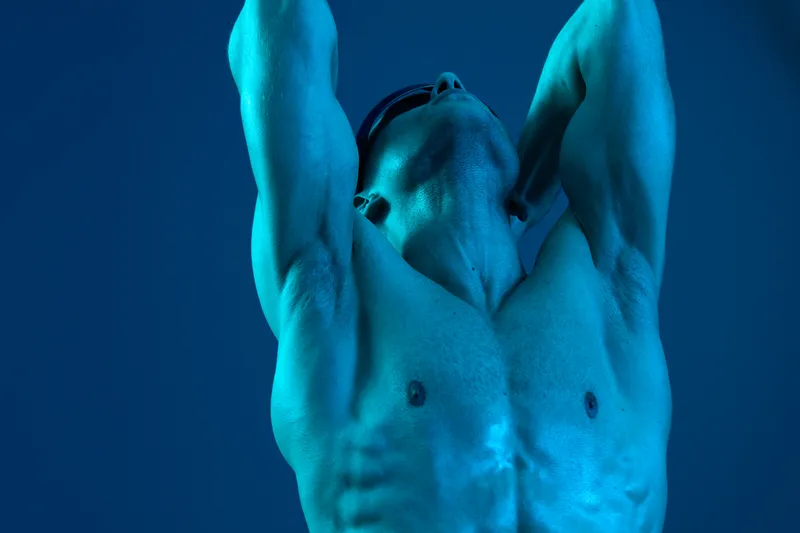 Athletic man celebrating after a workout, expressing joy and determination. The image features a vibrant blue hue, emphasizing energy and triumph in fitness.