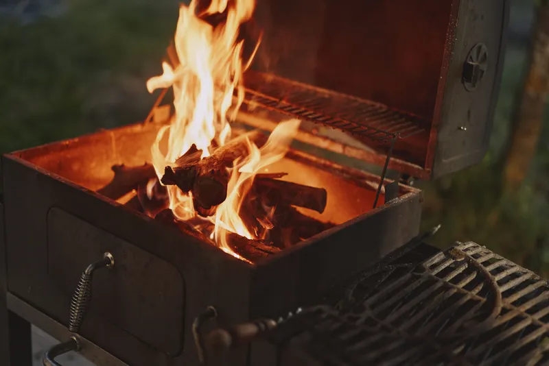 Cozy outdoor barbecue with flames, showcasing vibrant firewood in a grill, perfect for summer gatherings and culinary experiences
