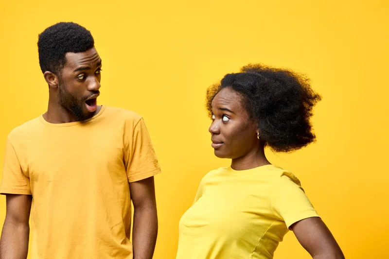 Two surprised models in yellow clothing expressing emotion against a vibrant yellow background, showcasing joy and surprise in a playful, energetic concept