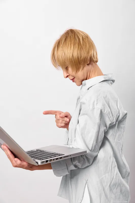 Child, laptop, technology, learning, blond, boy, stress, screen, standing in studio with white background, looking focused while using laptop, concept of digital education