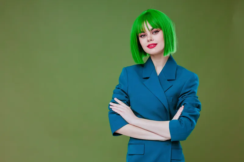 Молодая женщина, гламур, зеленый парик, красные губы, синяя куртка на зеленом фоне