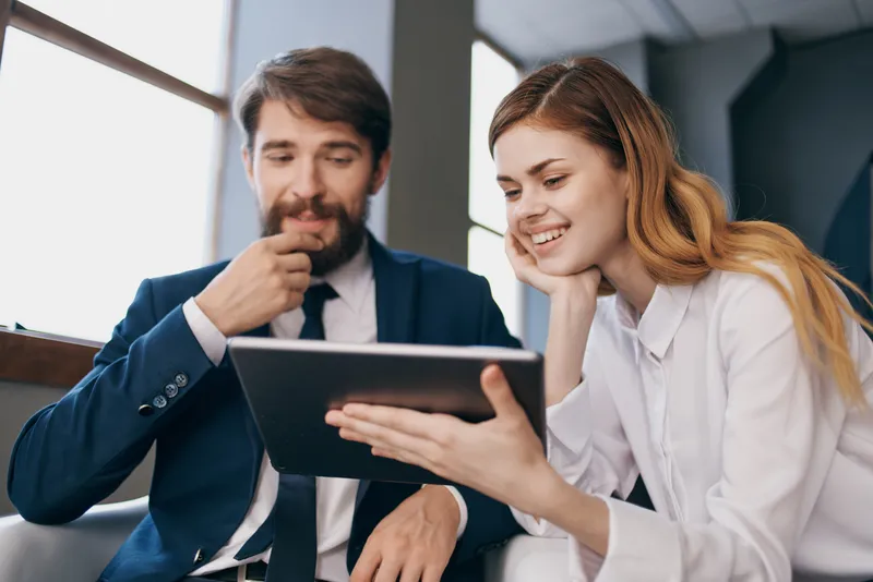 Бизнесмен и бизнес-леди смотрят на планшет в технологичном офисе