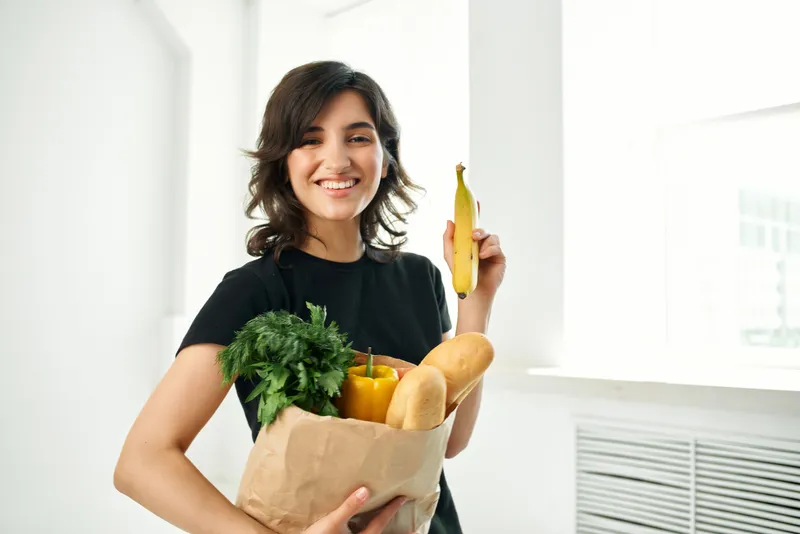 Весёлая брюнетка с сумкой для продуктов, доставка здоровой пищи, овощи
