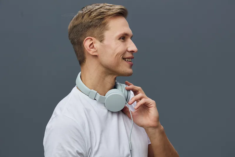 smiling man with headphones white t-shirt look side isolated on gray background studio portrait digital detox concept