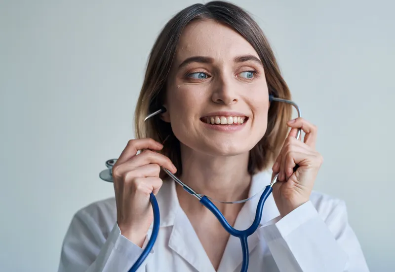 Профессиональная женщина-врач стоит у окна, на шее у нее стетоскоп