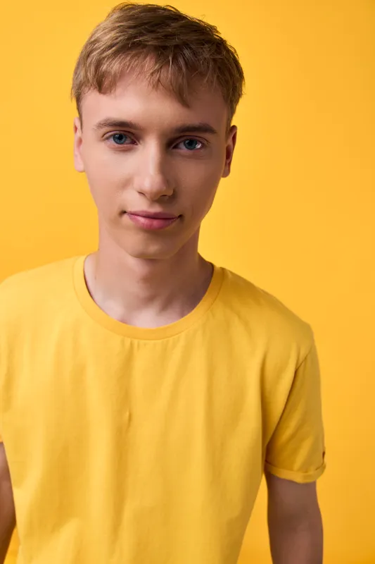 Youth, male, young man, casual fashion, studio shot with yellow background showcasing a clean, minimalist tee look, soft lighting, neat wardrobe for lifestyle or fashion stock
