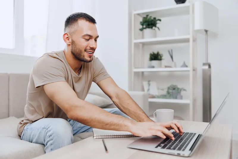 Smiling man working in a cozy indoor setting, showcasing productivity and creativity. Bright and modern workspace emphasizes a positive atmosphere and focus.