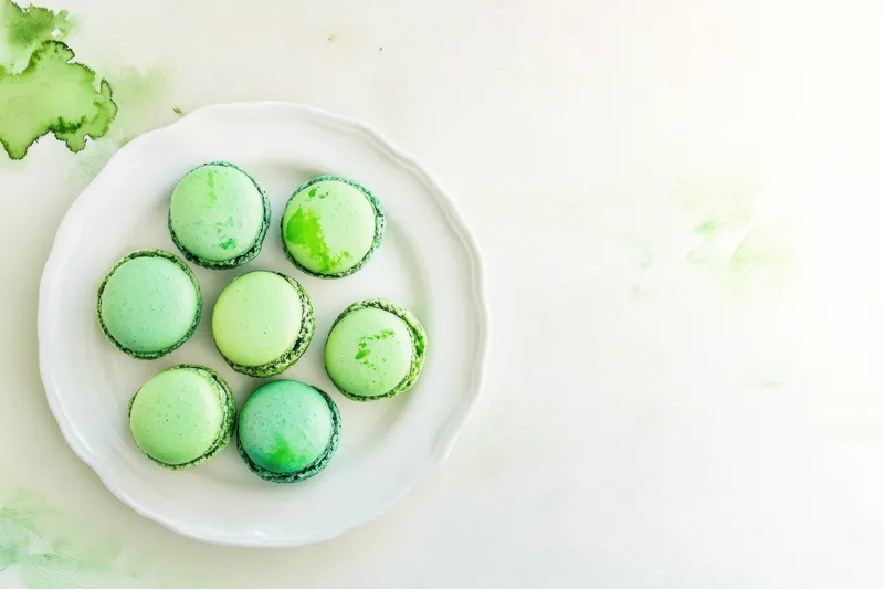 Вкусные зеленые макаруны, представленные на белой тарелке