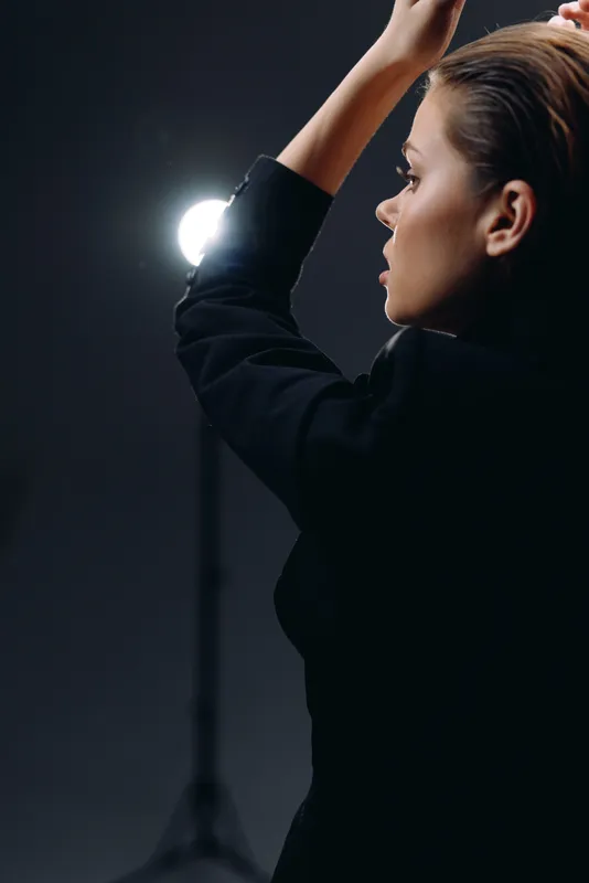 Profile of a thoughtful woman in black clothing with studio light background, reflecting calm and focus.