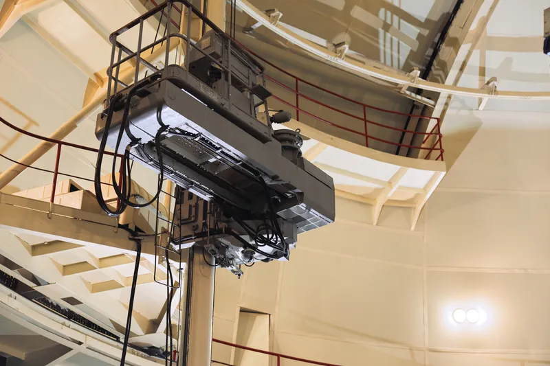 Крупная промышленная машина внутри заводского цеха с лестницей для технического обслуживания, демонстрирующая масштаб и функциональность производственного оборудования