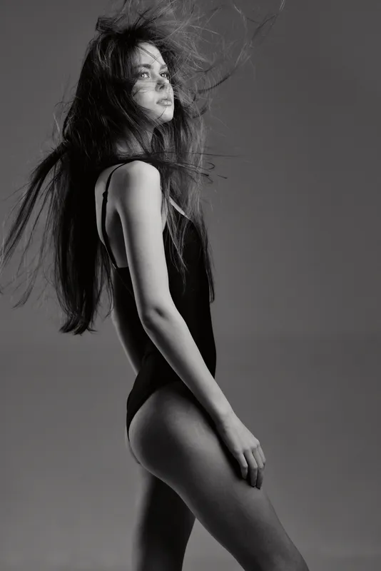 Black and white artistic portrait of a woman with flowing hair, showing elegance and motion in studio lighting.