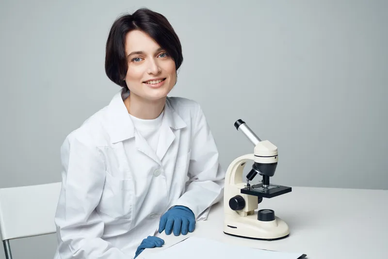 Женщина-учёный работает с микроскопом в лаборатории, занимаясь биотехнологиями