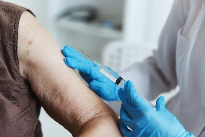 Врач делает инъекцию в руку, паспорт вакцинации от COVID-19 крупным планом
