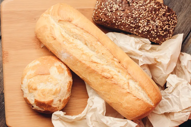 Мучные изделия, буханка хлеба и деревянная доска, светлый фон