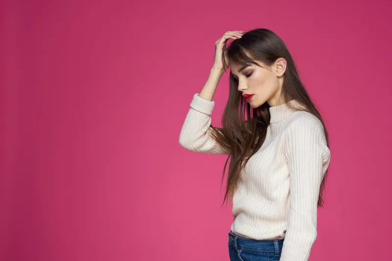 Красивая брюнетка с длинными волосами в модной одежде, элегантный стиль, розовый фон