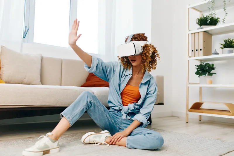 Виртуальная реальность веселье: женщина наслаждается футуристической VR-игрой дома с улыбкой